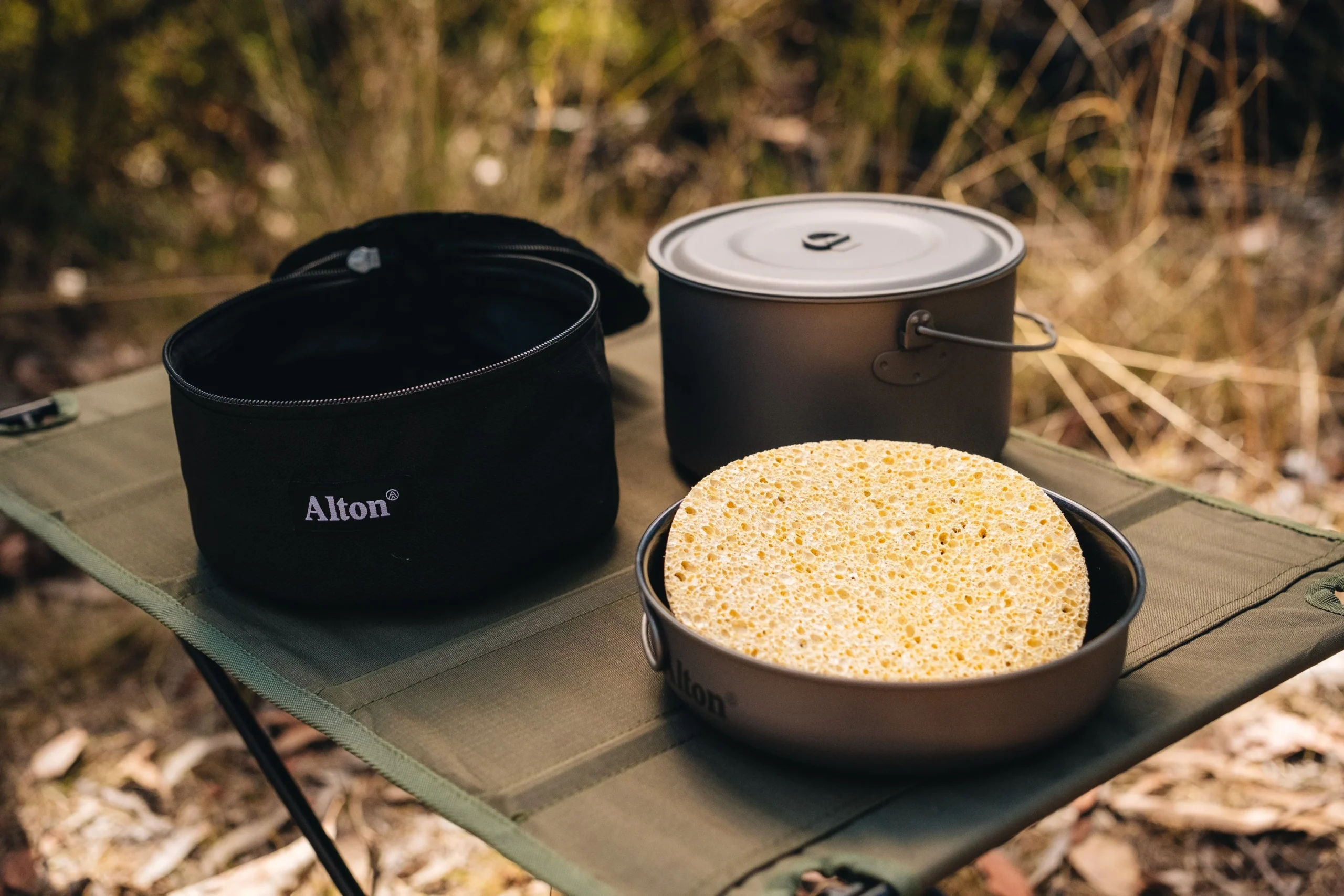 Backcountry cleaning titanium cookware at campsite - washing outdoor gear in wilderness setting