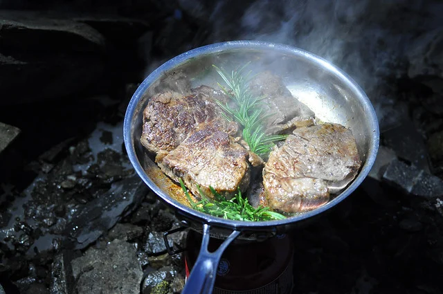 Batterie de cuisine de camping en titane : le guide honnête sur ce qu’elle fait (et ne fait pas) bien 3 Casserole de camping en titane posée sur un réchaud à cartouche, montrant un contact thermique centré – démonstration du « point chaud » pour les ustensiles de cuisine de randonnée